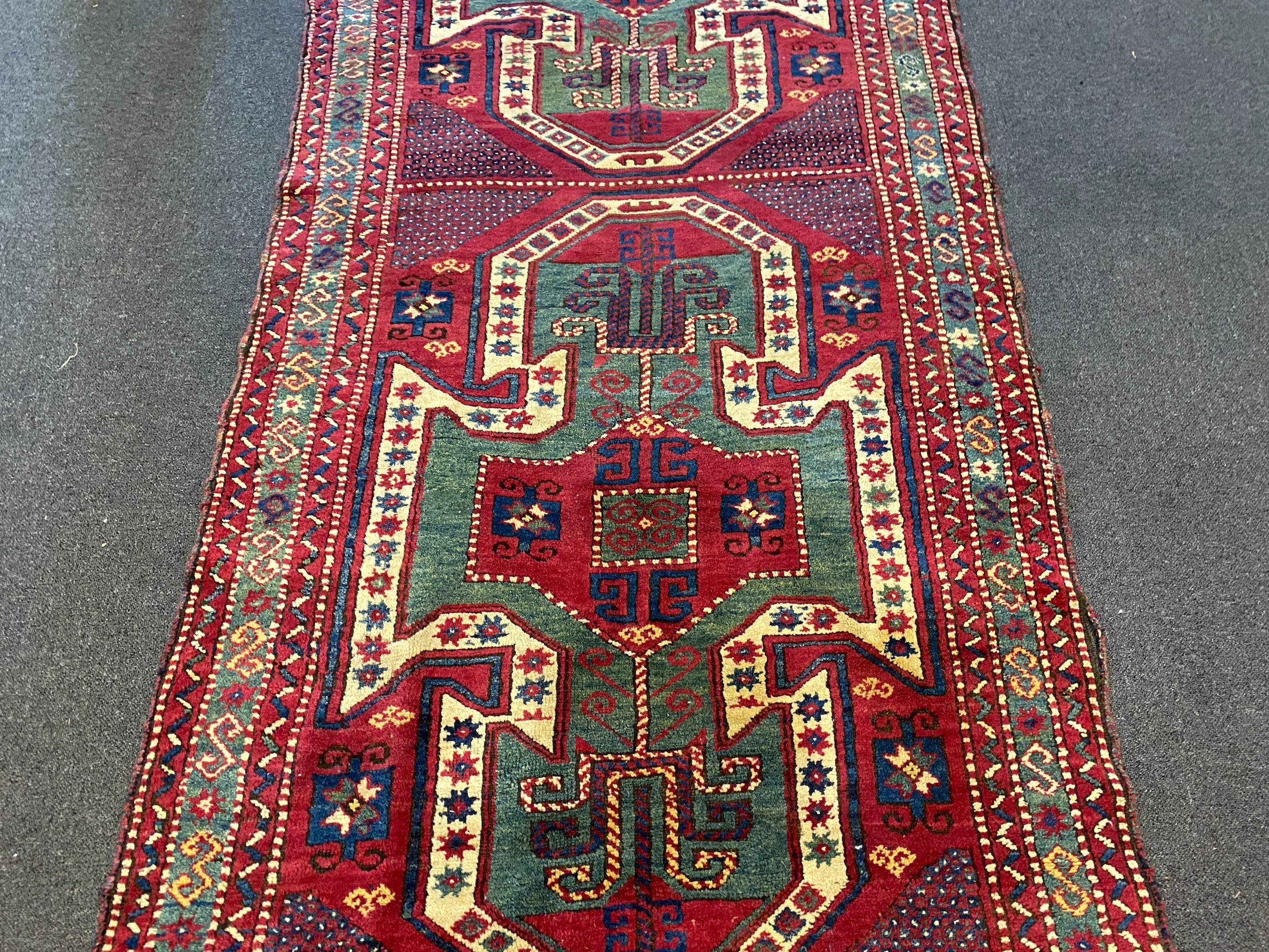 An antique Kazak red ground rug, 280 x 120cm